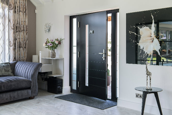 Modern interior with a black aluminium door, gray sofa, and decorative elements.