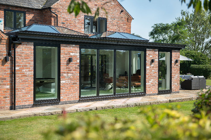 Modern extension of a brick house with large glass windows and doors.