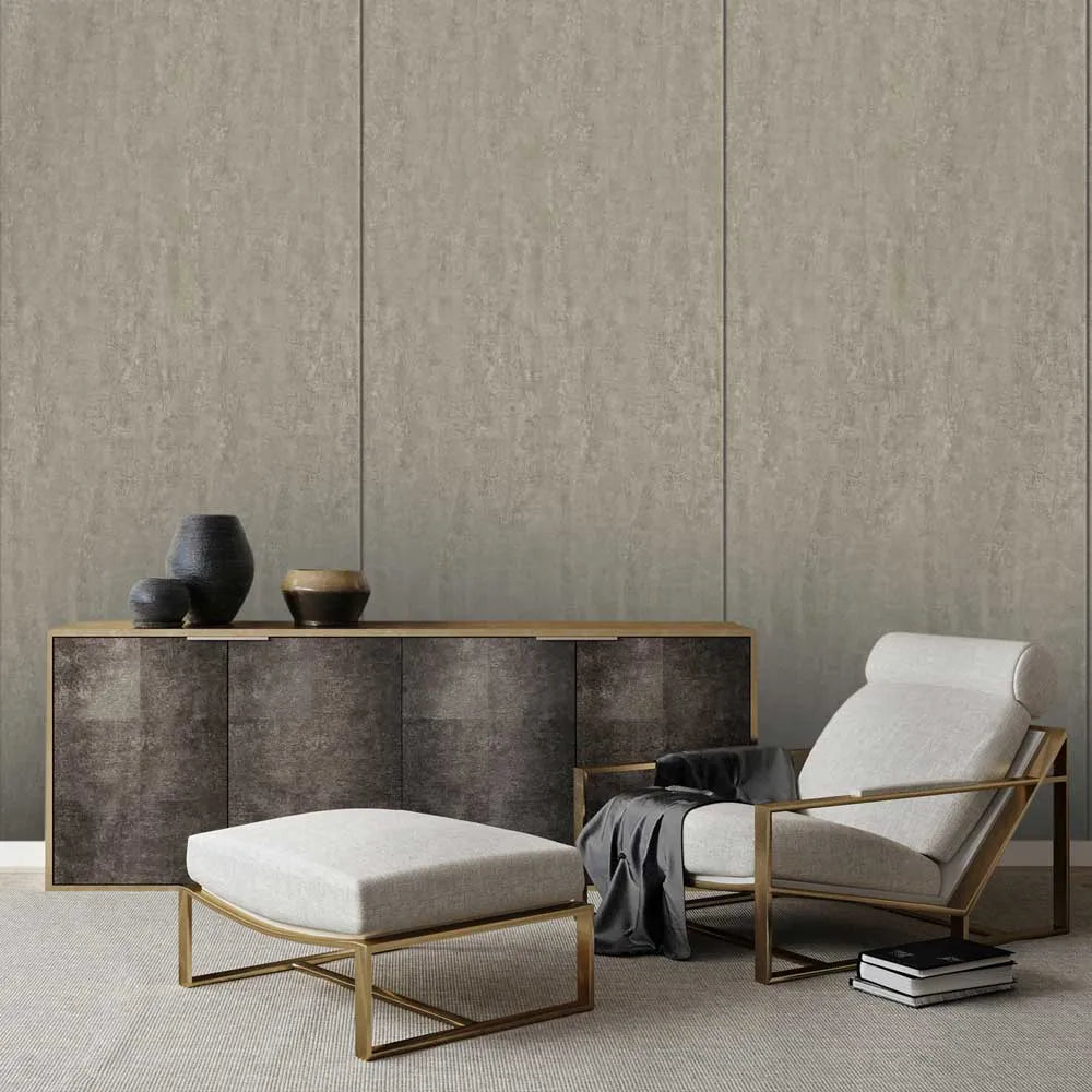 A modern living room setup featuring a light beige upholstered armchair with a gold metal frame, a matching beige ottoman with a gold frame, and a dark wood sideboard against a textured beige paneled wall.