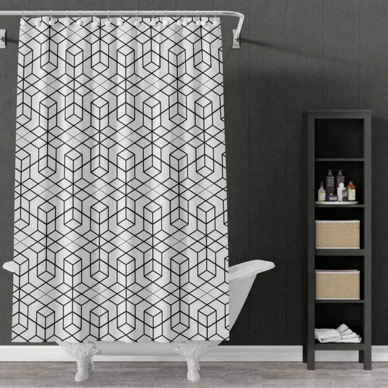 A white shower curtain with a black geometric cube pattern hanging in a bathroom next to a white clawfoot tub and a dark gray shelving unit.