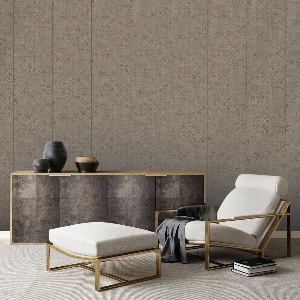 A styled interior scene showing a beige upholstered armchair with a gold metal frame, a matching ottoman, a dark wood sideboard with gold trim, and decorative vases against a patterned wallpaper background.