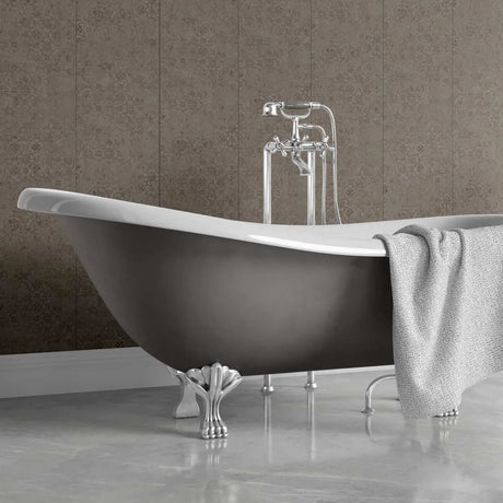 A freestanding bathtub with a dark charcoal exterior, white interior, and ornate silver claw feet, shown with a chrome faucet and a draped gray towel against a textured taupe tiled wall.