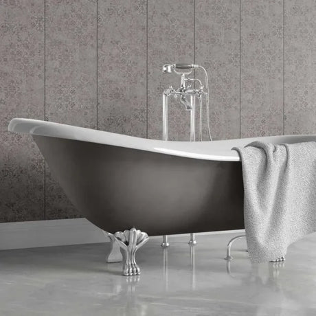 A freestanding bathtub with a matte dark gray exterior, white interior, and ornate silver claw feet, shown in a bathroom setting with a gray patterned tile wall and a draped gray towel.