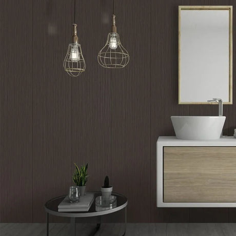 A modern bathroom scene with a floating vanity, white vessel sink, wood cabinet, mirror, and two hanging pendant lights with wire cages over dark brown wood-look wall panels.