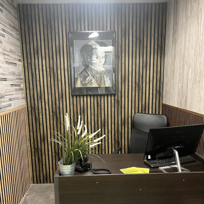 Reception area with a desk, computer, plant, and framed picture on a striped wall.