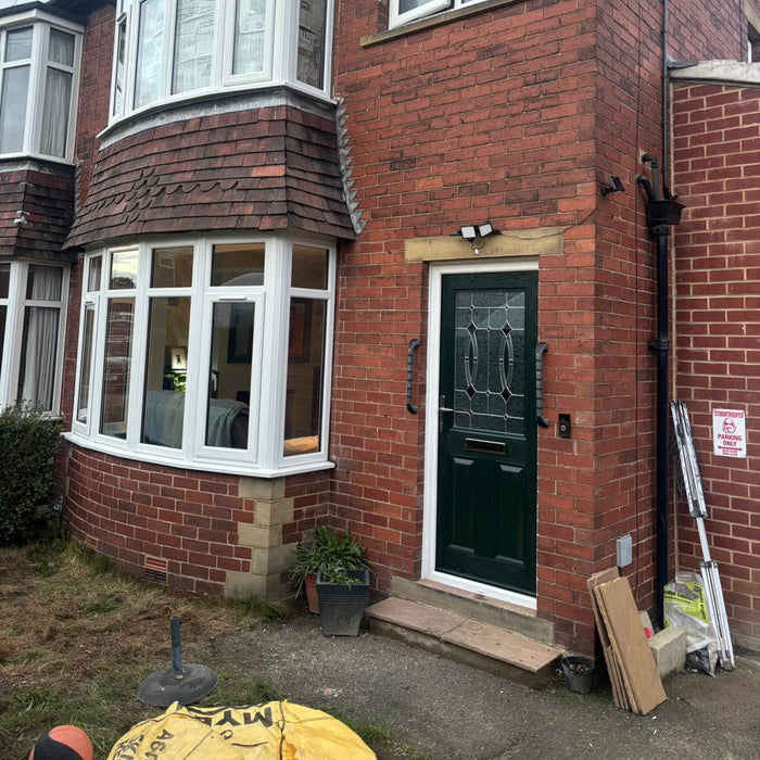 Brick house with a green door and white windows, showing construction or renovation work.