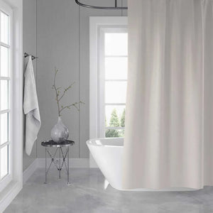 A white fabric shower curtain hanging in a bright, modern bathroom with gray paneled walls, a freestanding white tub, and a small side table with a vase.