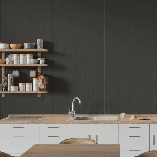 A modern kitchen scene with a large dark charcoal textured wall panel behind a light wood countertop, white cabinets, a sink, and floating wooden shelves holding dishes and mugs.