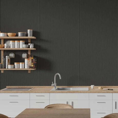 A modern kitchen scene with a large dark charcoal textured wall panel behind a light wood countertop, white cabinets, a sink, and floating wooden shelves holding dishes and mugs.