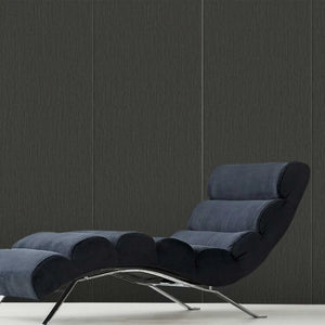 A modern lounge chair with a dark navy blue textured fabric and a chrome metal frame, set against a dark gray wood-paneled wall.