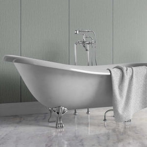 A freestanding oval bathtub with silver claw feet and a matching chrome faucet, shown in a bathroom setting with a gray towel draped over the side and a paneled wall behind it.