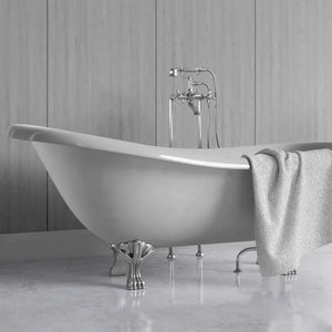 A freestanding oval bathtub with claw feet and a polished chrome faucet, shown in a bathroom setting with a gray towel draped over the side.