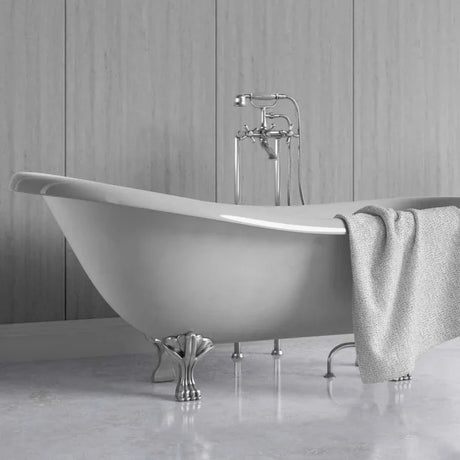A freestanding oval bathtub with claw feet and a polished chrome faucet, shown in a bathroom setting with a gray towel draped over the side.