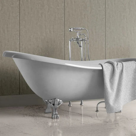 A freestanding oval bathtub with ornate silver claw legs and a matching chrome faucet set, shown in a bathroom with beige wall panels and a light gray towel draped over the side.