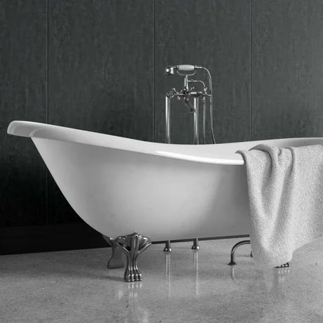 A freestanding white bathtub with ornate silver claw legs and a matching chrome faucet, shown in a bathroom setting with a gray textured towel draped over the side.