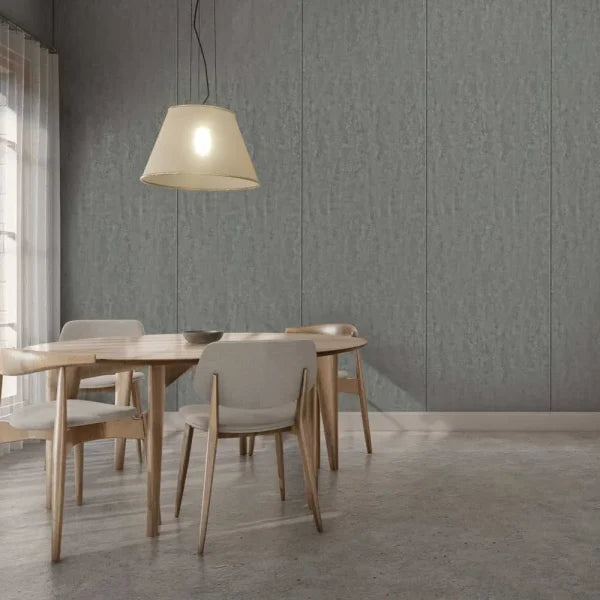 A modern dining room scene with a round light wood table and four upholstered dining chairs in a neutral gray setting, under a hanging pendant lamp against a paneled gray wall.