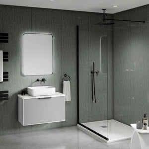 Modern floating bathroom vanity with a white rectangular sink, a large rectangular mirror, and a ribbed white cabinet set against dark gray textured walls. A glass shower enclosure with black trim is visible to the right.