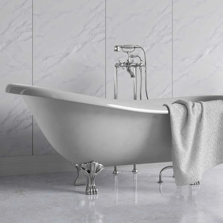 A freestanding oval bathtub with claw feet and a polished chrome faucet set, shown in a bathroom with light marble wall and floor tiles. A textured light gray towel is draped over the side of the tub.