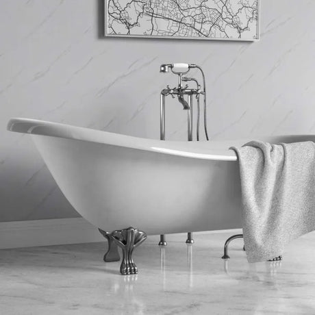 A white freestanding clawfoot bathtub with a polished chrome faucet and matching shower hose, set in a bathroom with a gray marble floor and wall. A gray towel is draped over the side of the tub, and a framed city map hangs on the wall above.