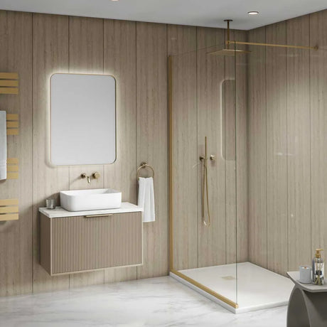 Modern bathroom vanity and walk-in shower enclosure in a light wood-paneled bathroom. The vanity features a white rectangular vessel sink, a ribbed beige cabinet, a large rounded rectangular backlit mirror, and brass fixtures.