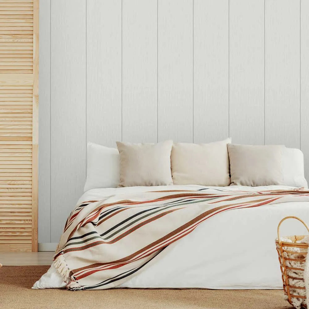 Beige sofa with striped blanket and woven basket against a light wooden panel wall.