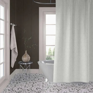 A white textured shower curtain hanging in a modern bathroom with dark wood paneled walls, a white freestanding tub, and a black-and-white speckled floor.