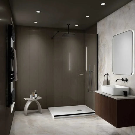 A modern bathroom interior with a walk-in shower enclosure, white vessel sink, dark wood vanity, and a large rectangular mirror on a light stone wall.