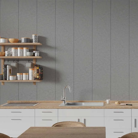 A modern kitchen interior with a gray paneled wall, white lower cabinets, a light wood countertop, a built-in sink, and floating wooden shelves holding jars and bowls.