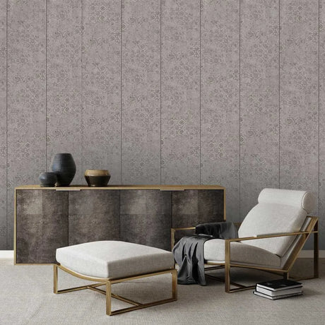 A styled interior scene showing a patterned wallpapered wall behind a console cabinet, ottoman, and armchair with gold-toned metal frames and light upholstery.
