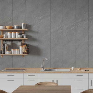 A modern kitchen interior with a large gray stone-look tiled backsplash, white lower cabinets, a light wood countertop, a built-in sink, and open wooden shelves holding jars and cookware.