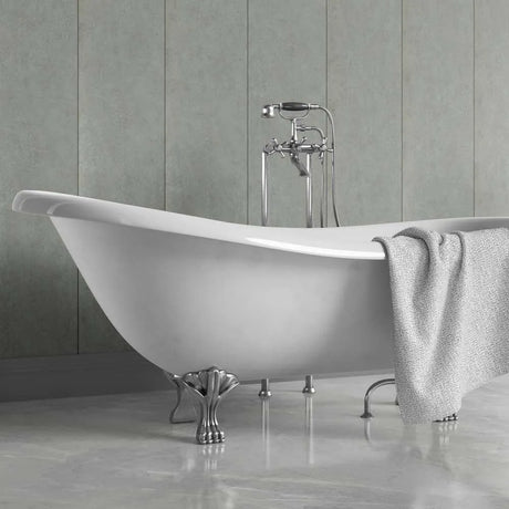 A white freestanding clawfoot bathtub with polished silver metal legs and a matching chrome faucet set, shown in a bathroom with gray paneled walls and a gray bath towel draped over the side.