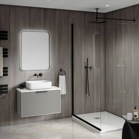 Modern bathroom interior featuring a floating white vanity with a rectangular vessel sink, a large rectangular mirror, and a walk-in shower with clear glass doors and black trim.