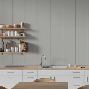 A modern kitchen interior with white cabinets, a light wood countertop, a built-in sink and faucet, open wooden shelves with jars and books, and a gray paneled wall behind.