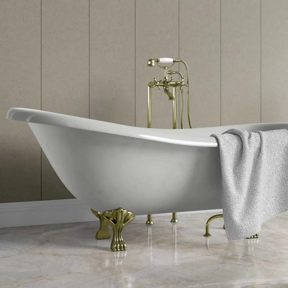A freestanding oval bathtub with ornate gold-tone claw feet and a matching gold faucet, shown in a bathroom setting with a gray towel draped over the side.