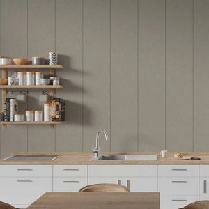 A modern kitchen interior with white cabinets, a light wood countertop, a stainless steel sink and faucet, open wooden shelves with jars and books, and a large taupe-beige paneled wall behind the counter.