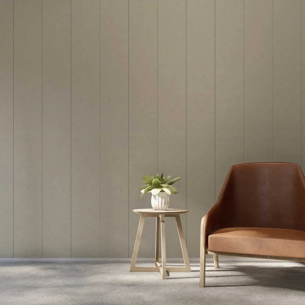 A modern interior scene with a brown leather armchair on the right and a small round wooden side table holding a potted plant, set against a beige paneled wall and gray floor.