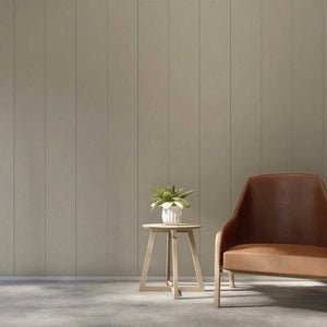 A modern interior scene with a brown leather armchair on the right and a small round wooden side table holding a potted plant, set against a beige paneled wall and gray floor.