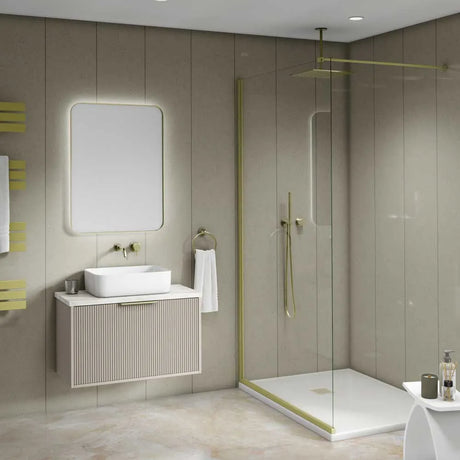 A modern bathroom interior featuring a floating vanity with a white vessel sink, a large rectangular backlit mirror, and a walk-in shower with clear glass panels and brass-toned trim.