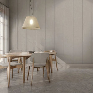 A modern dining room scene with a light wood table and four upholstered chairs in neutral tones, under a hanging pendant lamp against a paneled wall.
