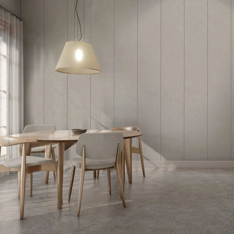 A modern dining room scene with a light wood table and four upholstered chairs in neutral tones, under a hanging pendant lamp against a paneled wall.