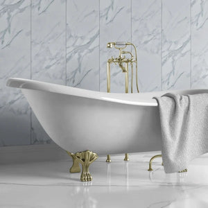 White freestanding bathtub with gold legs and fixtures against a marble wall.