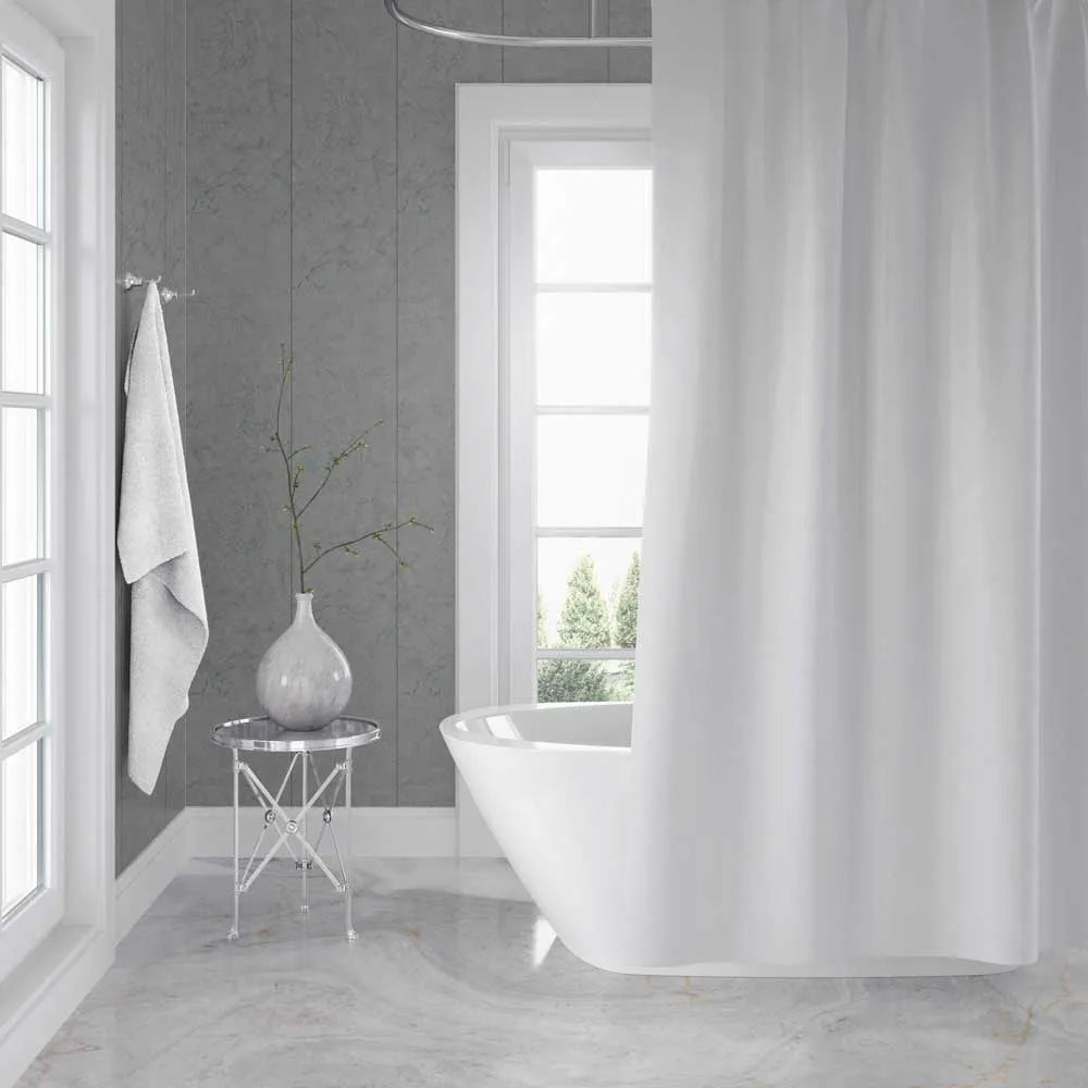 A white fabric shower curtain hanging in a bright, modern bathroom with gray paneled walls, a freestanding white tub, and a small side table with a vase.