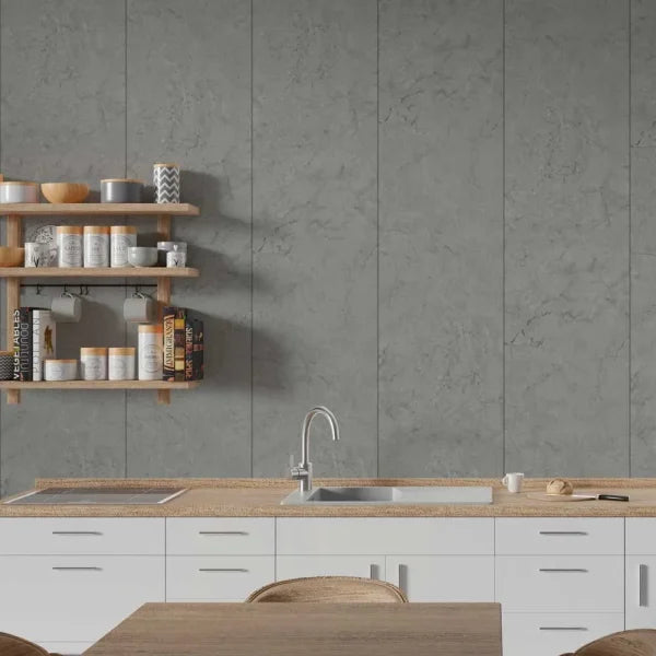 A modern kitchen interior featuring large gray stone-look wall tiles behind a white countertop with a built-in sink and faucet, plus light wood floating shelves with canisters and cookware.