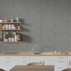A modern kitchen interior featuring large gray stone-look wall tiles behind a white countertop with a built-in sink and faucet, plus light wood floating shelves with canisters and cookware.