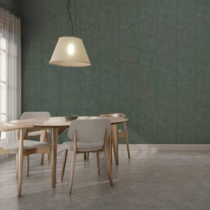 A modern dining room scene featuring a round wooden dining table and four upholstered chairs in a neutral gray and beige color palette, set against a prominent textured dark green paneled wall under a hanging pendant light.
