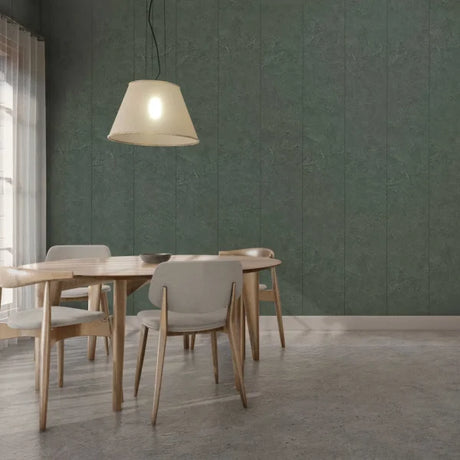 A modern dining room scene featuring a round wooden dining table and four upholstered chairs in a neutral gray and beige color palette, set against a prominent textured dark green paneled wall under a hanging pendant light.