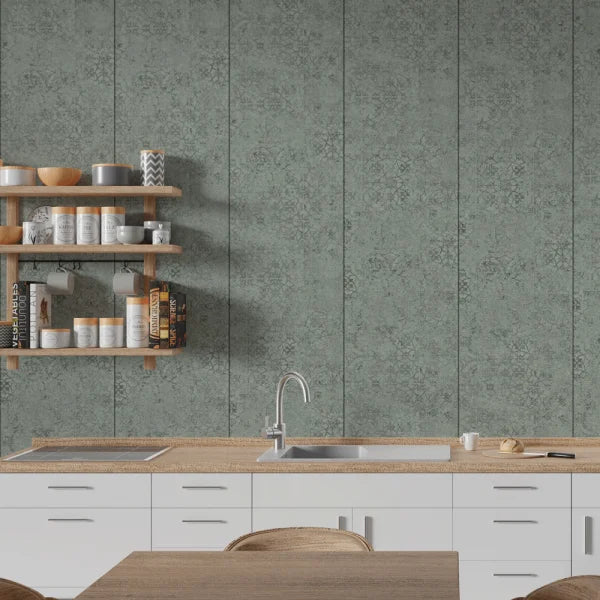A modern kitchen interior featuring sage green patterned wall panels behind white cabinets and a light wood countertop with a sink and faucet. Floating wooden shelves on the left hold jars, bowls, and books.