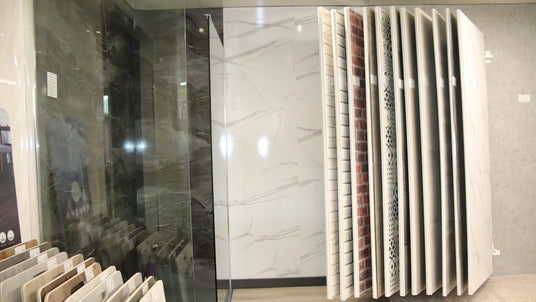 Display of various tiles with a marble pattern in a showroom setting.