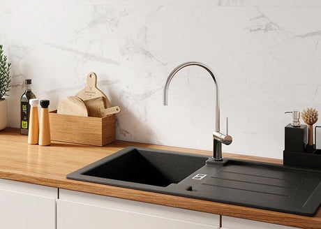 Modern kitchen sink with faucet on a wooden countertop against a Calacatta snow background.