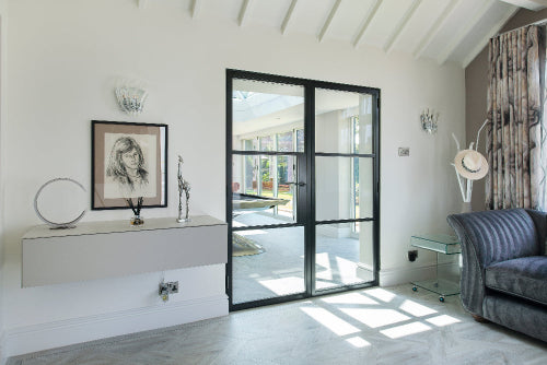 Modern living room with a glass door leading to a patio, featuring a sofa, coffee table, and decorative items.